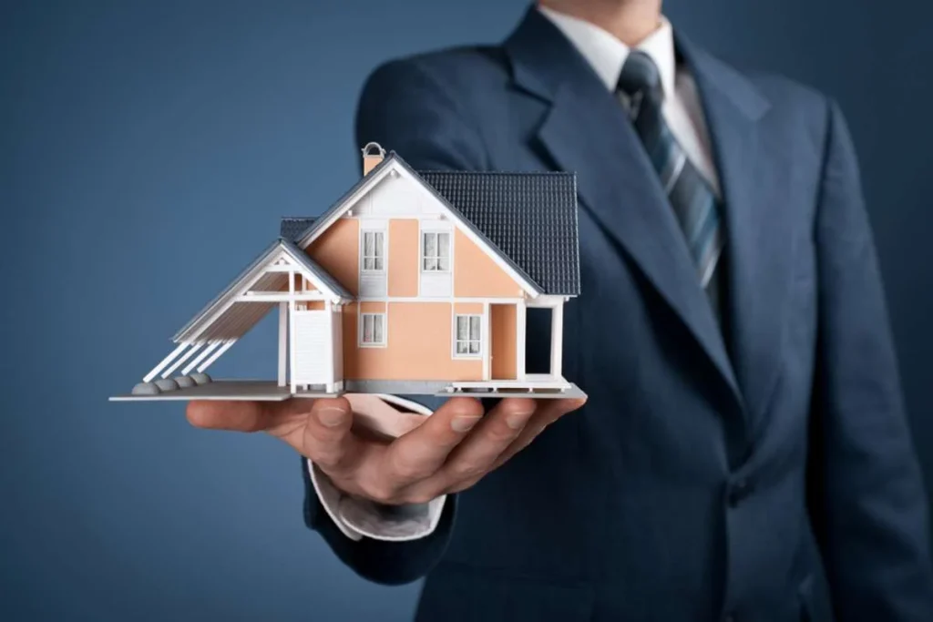 A striking image: A man in a suit holding a house emblem atop his hand, with the spotlight on the intricate house design