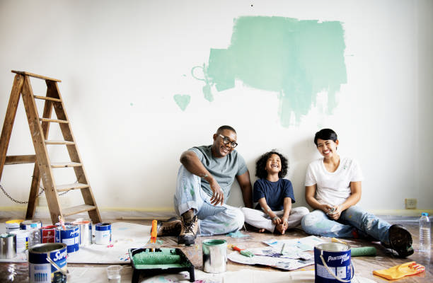 Three family members sit together, diligently fixing their house, their faces reflecting satisfaction.